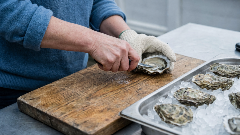 Fresh oysters being shucked on site on a timber board